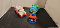 Three small Transformers Rescue Bots vehicles on black surface