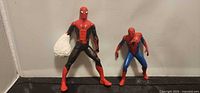 Both Spider-Man figures standing side by side on black surface
