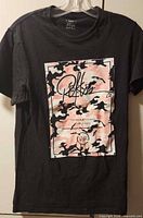 Front view of black t-shirt hanging, showing full graphic and size indication