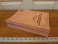 Stack of twelve salmon-pink exercise books side view