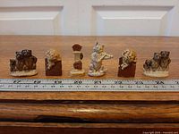 Six Wade Whimsies porcelain figurines lined up with ruler for scale