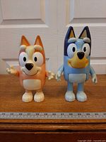 Front view of both Bluey and Bingo figures with ruler for scale