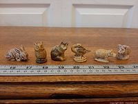 All six Wade Whimsies figurines lined beside ruler