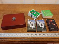 Overview showing wooden box and five card decks with ruler for scale