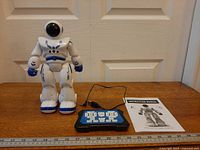 Full lot showing robot, remote, cable, manual with ruler for scale