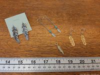 Group image of all earrings and pendant beside ruler for scale