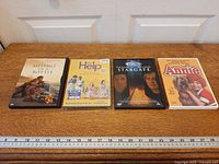 Four DVD cases laid out showing fronts and ruler for scale