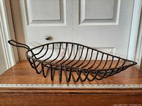 Leaf-shaped basket side view on table with ruler for scale