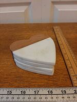 Stack of four heart marble/wood coasters beside rulers for scale