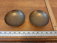 Top view of two shallow brass bowls beside ruler showing diameter ~4.25 in
