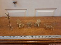 All five brass-finished miniature furniture pieces lined up next to ruler for scale