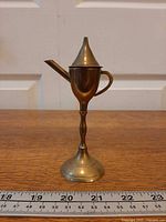 side view displaying spout, handle, conical lid, pedestal base