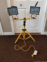 Full view of yellow tripod work light with two heads and cord