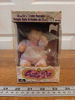 Front view of boxed Cutie Pie doll with ruler for scale