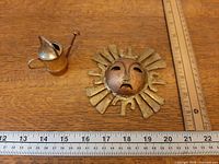 Sun sculpture and watering can with ruler for scale