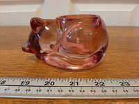 Side view of pressed glass sleeping cat tealight holder with ruler showing length