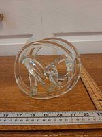 Front view of clear glass knot sculpture with rulers showing width ~6 inches