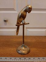 Full view of brass parrot on stand with ruler for scale