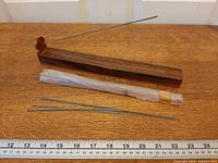 Wooden incense holder, wrapped incense bundle, loose sticks, ruler for scale