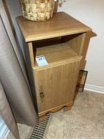 Front view of light oak cabinet showing open shelf and door with brass hardware