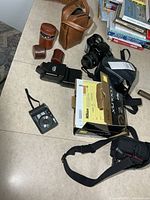 All items on tabletop including Nikon box, Minolta camera, Vivitar flash, two brown lens cases, strap