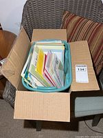 Open cardboard box showing turquoise plastic bin filled with greeting cards