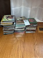 Two stacks of approximately 50 CDs on hardwood floor