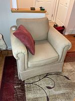 Front view of beige corduroy armchair with burgundy pillow