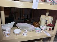 Shelf view showing china, coaster set, candle and decor
