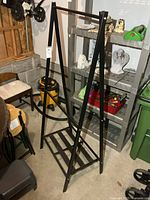 Full view of black metal A-frame garment rack showing top bar and bottom slatted shelf