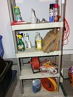 Full view of shelf showing cord reel, extension cords, washer fluid jugs, weed sprays, yard bags