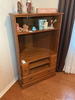 Front view of oak corner cabinet showing shelves and drawer