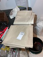 Folded beige curtain panels with MaxSold lot tag