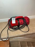 Full view of Dirt Devil handheld vacuum coiled with cord on steps