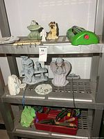 Shelf with resin figurines, sprinkler, tool caddy