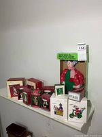 Full view of all boxed ornaments and animated doll on shelf