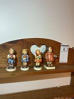 Front view of all four Hummel figurines on shelf