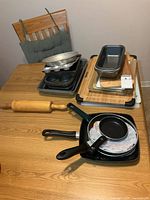 Group shot of all cookware, bakeware, cutting boards and rolling pin on table
