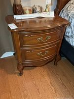 Front view showing two drawers with brass pulls and curved front