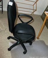 Side view of black office chair on clear mat