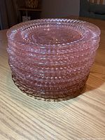 Stack of 11 pink glass plates on table