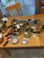 Grouping of stainless pots, pans, copper bottoms, lids, and two non-matching small saucepans