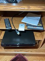 Player, remote, HDMI cable, manuals and disc cases on shelf
