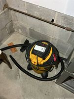 Vacuum canister on floor with hose coiled