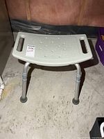 Front view of shower chair showing seat surface, handles, legs and rubber tips