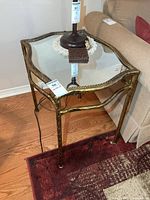 Angled view of metal side table next to sofa, showing mirror top and frame