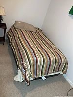 Single bed fully made with striped comforter and pillow