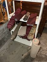 Multiple rolled small rugs on white rack