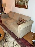 front angled view of beige corduroy sofa with pillow