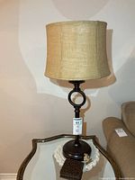 Entire lamp on side table with shade and coasters visible
